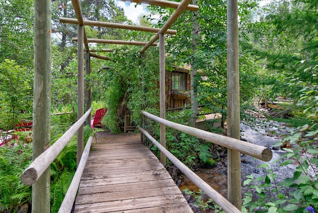 wooden deck with a water view and a pergola