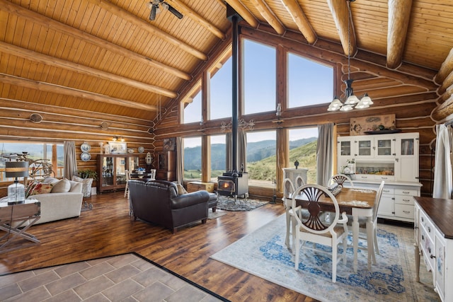 living room with a wood stove, an inviting chandelier, a mountain view, high vaulted ceiling, and beamed ceiling