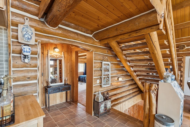 hallway featuring wooden ceiling, dark tile patterned flooring, log walls, and beam ceiling