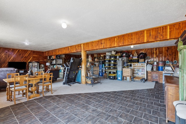 basement featuring wooden walls and a textured ceiling