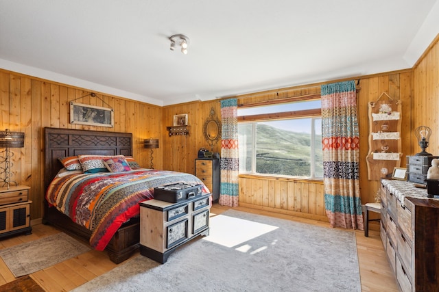 bedroom featuring light hardwood / wood-style floors and wood walls