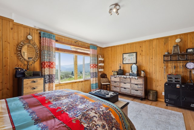 bedroom with a mountain view, light hardwood / wood-style floors, and wooden walls