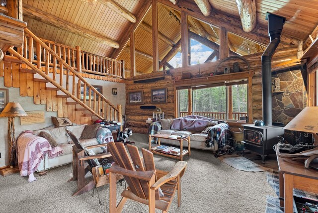 carpeted living area featuring wood ceiling, a wood stove, stairway, and beam ceiling