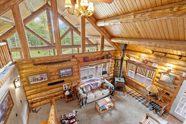 carpeted living area with wood ceiling, a wood stove, a notable chandelier, and beamed ceiling