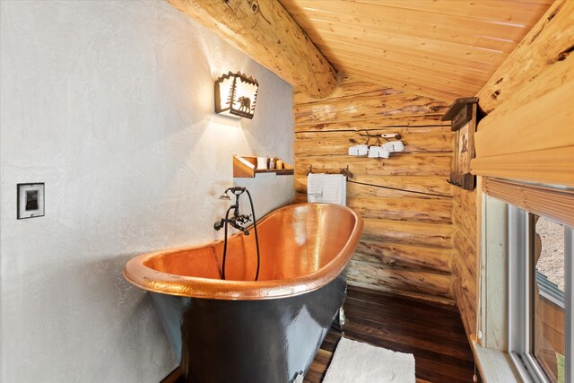 interior space featuring lofted ceiling, wooden ceiling, a freestanding tub, and log walls