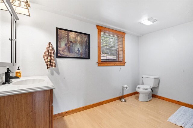 bathroom with toilet, baseboards, wood finished floors, and vanity