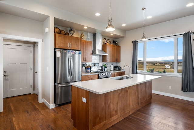 kitchen featuring sink, decorative light fixtures, a center island with sink, wall chimney exhaust hood, and appliances with stainless steel finishes