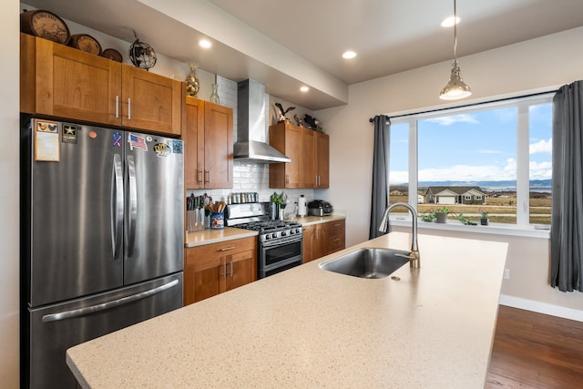 kitchen with hanging light fixtures, sink, wall chimney range hood, appliances with stainless steel finishes, and dark hardwood / wood-style flooring