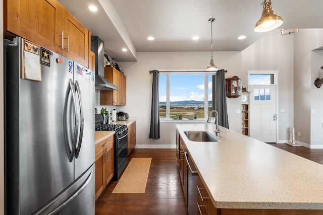 kitchen featuring an island with sink, stainless steel appliances, hanging light fixtures, and sink