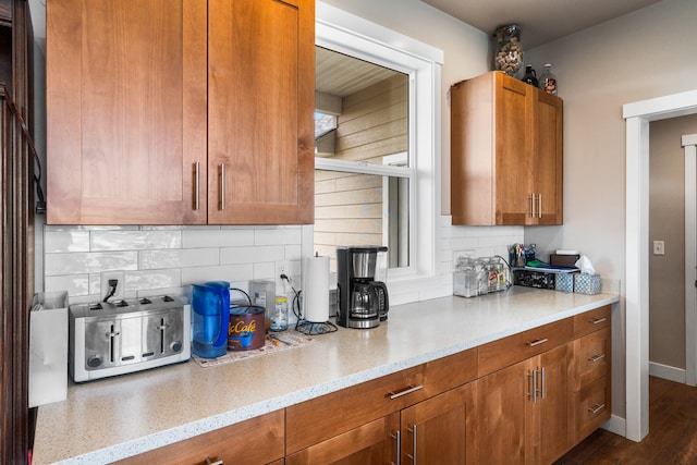 kitchen featuring decorative backsplash, light stone countertops, and dark hardwood / wood-style flooring