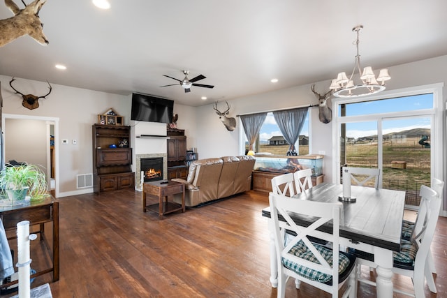 dining space with ceiling fan with notable chandelier and dark hardwood / wood-style floors