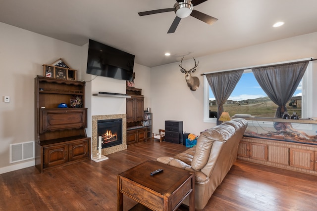 living room with dark hardwood / wood-style floors, a tiled fireplace, and ceiling fan