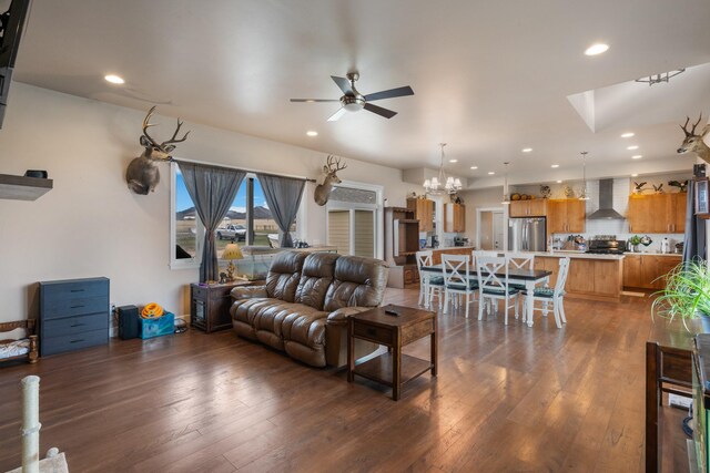 living room featuring ceiling fan with notable chandelier and dark hardwood / wood-style floors