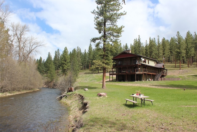 view of home's community featuring a deck with water view and a lawn