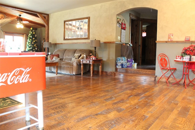 living room with wood-type flooring, ceiling fan, and beamed ceiling