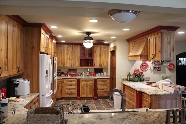 kitchen with white fridge with ice dispenser, light stone countertops, tile flooring, sink, and ceiling fan