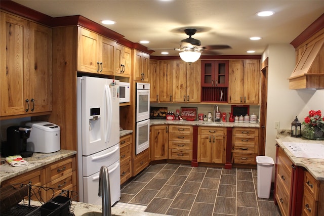 kitchen featuring ceiling fan, dark tile floors, sink, white appliances, and light stone countertops