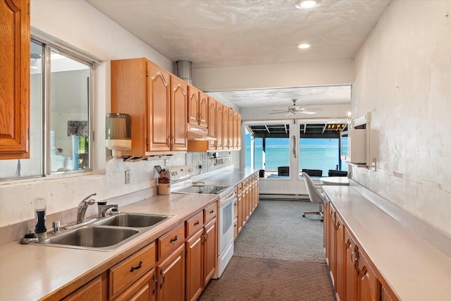 kitchen featuring sink, a baseboard radiator, white range with electric stovetop, carpet floors, and ceiling fan