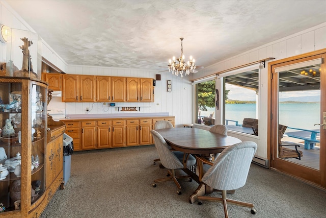 carpeted dining area with ornamental molding, a water view, and an inviting chandelier