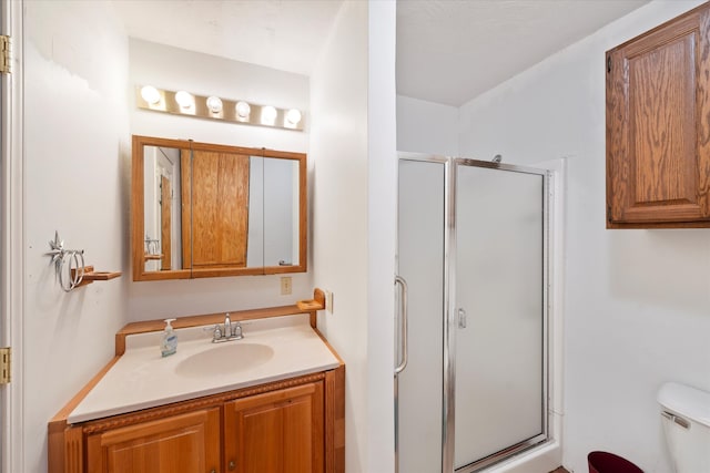 bathroom with toilet, a shower with door, and vanity