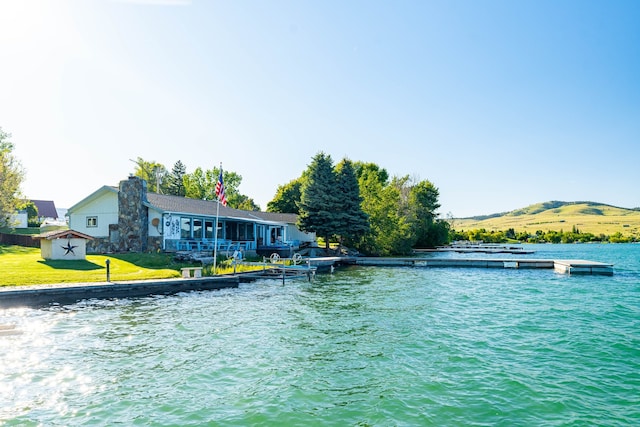 view of swimming pool with a lawn, a dock, and a water and mountain view