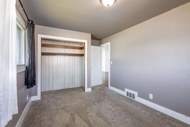 unfurnished bedroom with carpet floors, a closet, and wooden walls