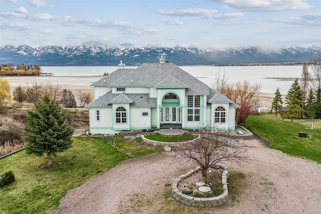 french country inspired facade featuring a water and mountain view, a front lawn, and french doors