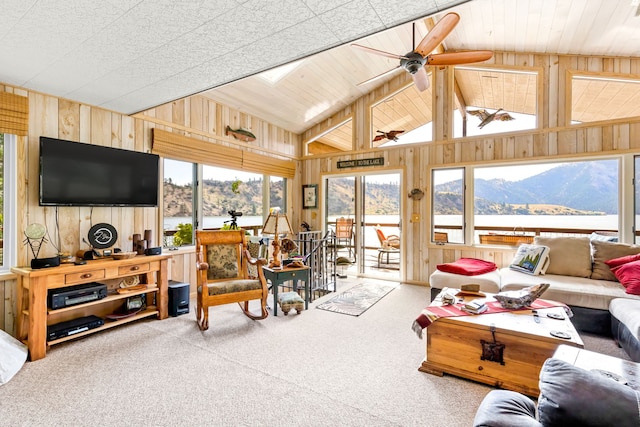 carpeted living room with vaulted ceiling, wood walls, ceiling fan, and a water and mountain view