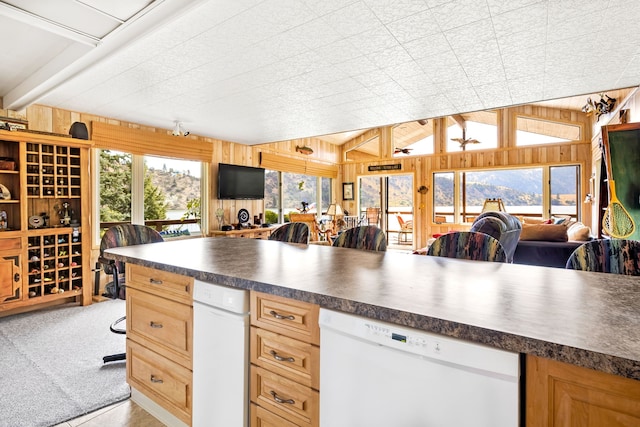 kitchen with wood walls, light colored carpet, dishwasher, and vaulted ceiling with beams