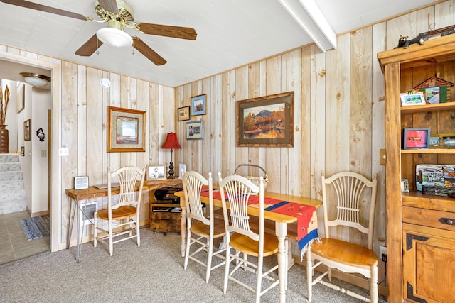 dining room featuring ceiling fan, carpet flooring, and wooden walls