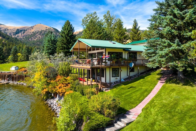 back of property with a yard and a deck with water view