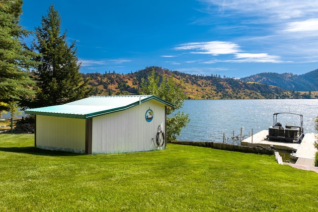 view of dock with a water and mountain view and a lawn