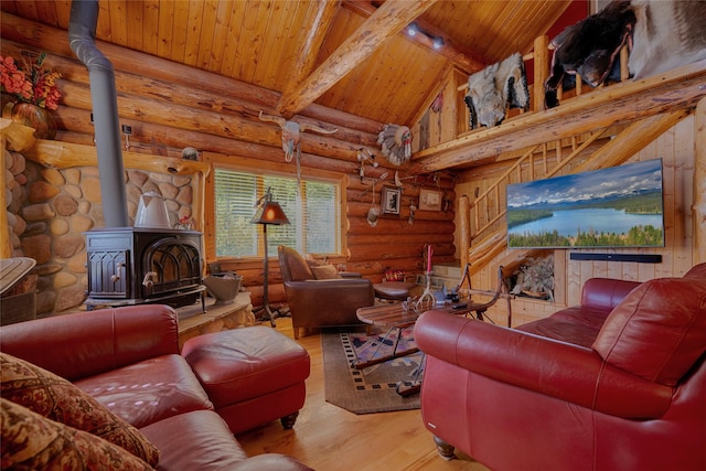 living room with rustic walls, a wood stove, beamed ceiling, wood ceiling, and wood finished floors