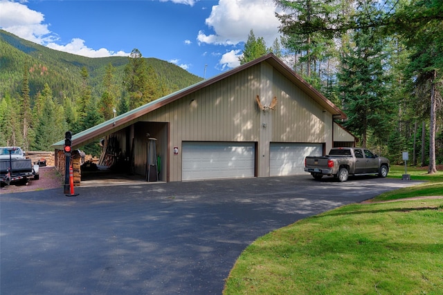 view of side of home featuring a garage, a mountain view, and a wooded view