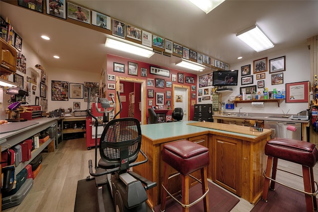 bar with indoor wet bar, light wood finished floors, recessed lighting, and stainless steel dishwasher