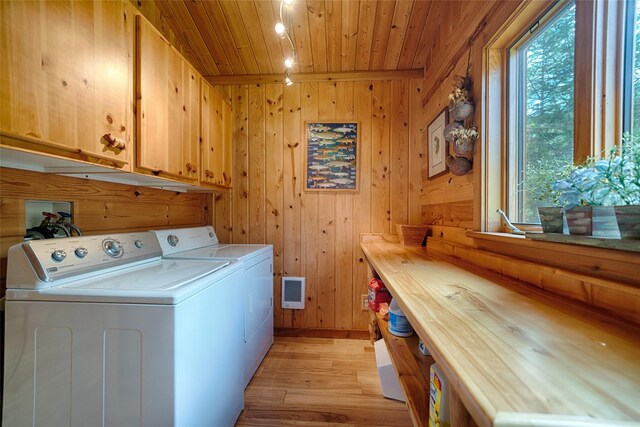 laundry room with washer and dryer, light wood-type flooring, wood ceiling, wooden walls, and cabinet space