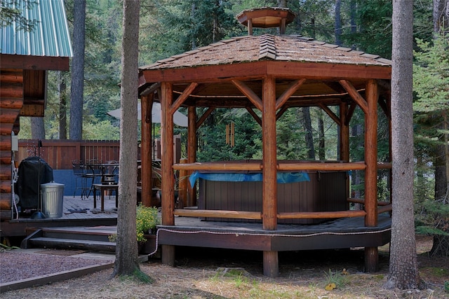 view of property's community featuring a wooded view, a jacuzzi, a gazebo, and fence