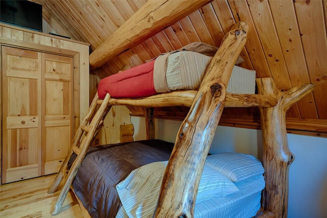 bedroom with vaulted ceiling with beams, wooden ceiling, and wood finished floors