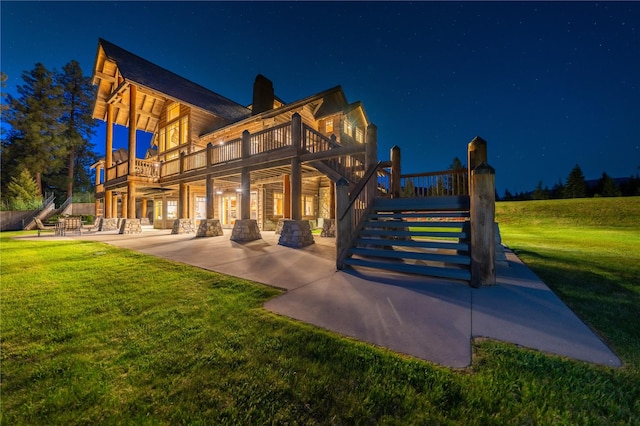 back of house at twilight with a patio area, stairway, a deck, and a lawn