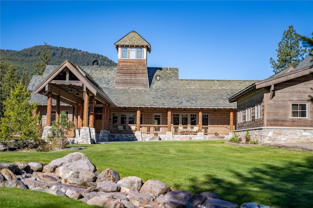 rear view of house featuring a mountain view and a lawn