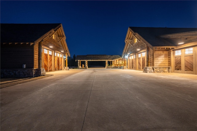 property exterior at twilight with a garage, stone siding, and driveway