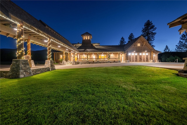 back of house at night featuring a lawn