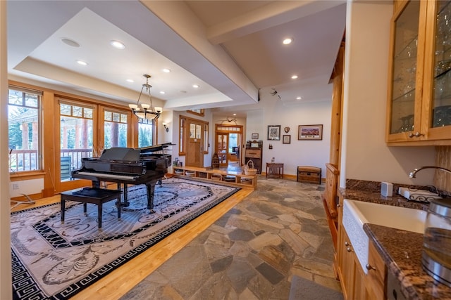 interior space with baseboards, stone finish floor, an inviting chandelier, a tray ceiling, and recessed lighting