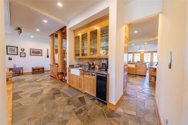 bar featuring baseboards, dishwasher, dishwashing machine, stone tile flooring, and a sink