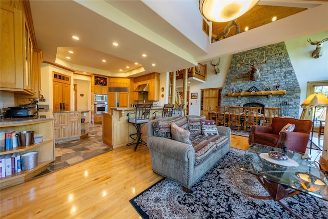 living area with recessed lighting, a raised ceiling, visible vents, stairway, and light wood-style floors