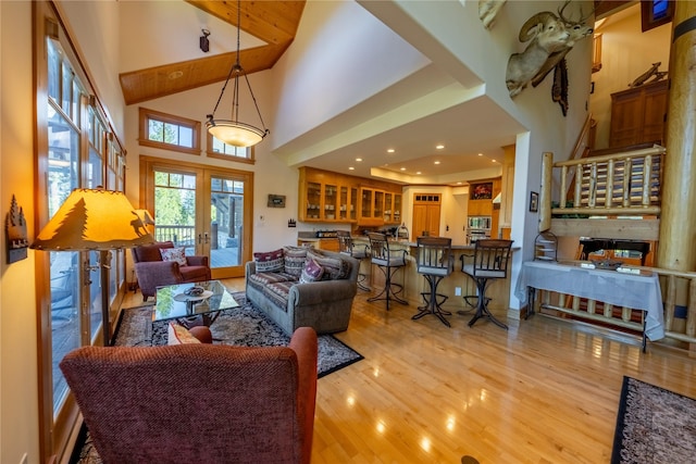 living room featuring french doors, a high ceiling, and light wood-style flooring