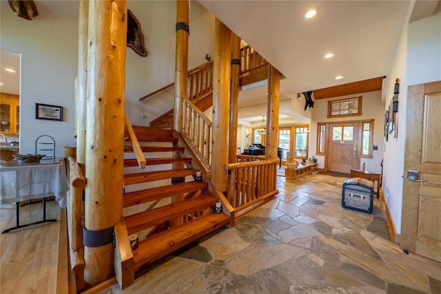 foyer entrance with stone finish flooring, stairs, and recessed lighting