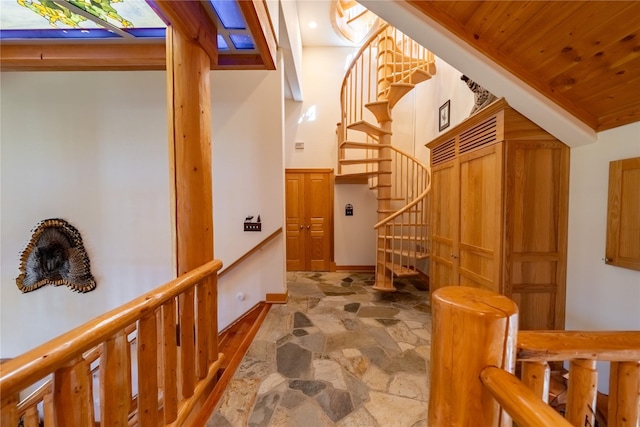 hallway featuring stairs, stone finish flooring, wood ceiling, and baseboards