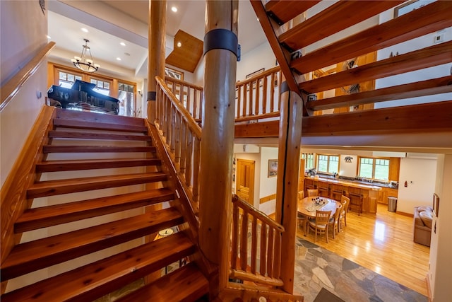 stairway featuring stone finish flooring, a high ceiling, a notable chandelier, and recessed lighting