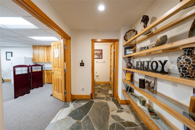 hall featuring baseboards, dark carpet, a drop ceiling, and recessed lighting